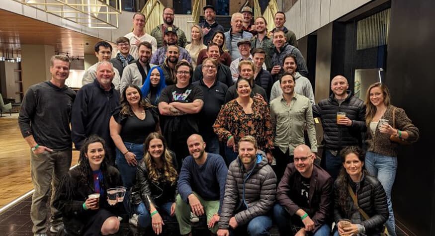 A diverse company team gathered on stairs in a contemporary office lobby for a group portrait.