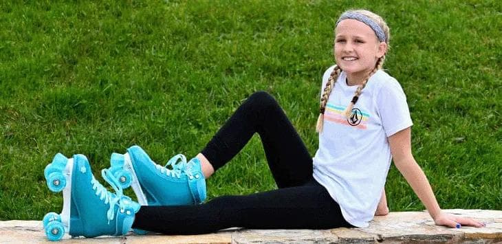 Crazy skate life - Young girl sitting on a stone ledge wearing bright teal Crazy Skate roller skates with matching wheels.