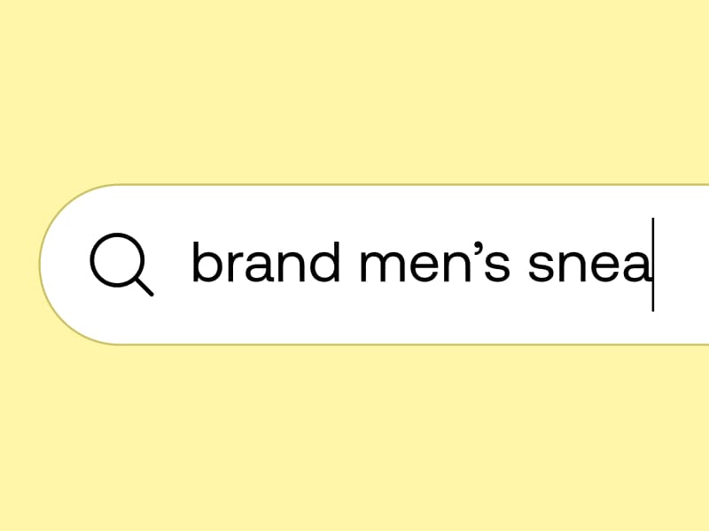 A close-up of a search bar on a yellow background with the text "brand men's snea" being typed.