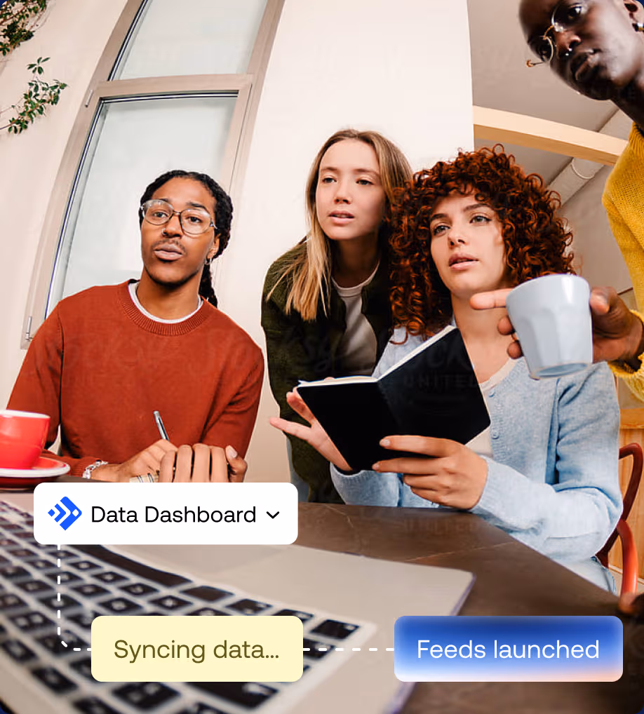 A team collaborating around a laptop with UI overlays for a Data Dashboard showing syncing data and feeds launched.