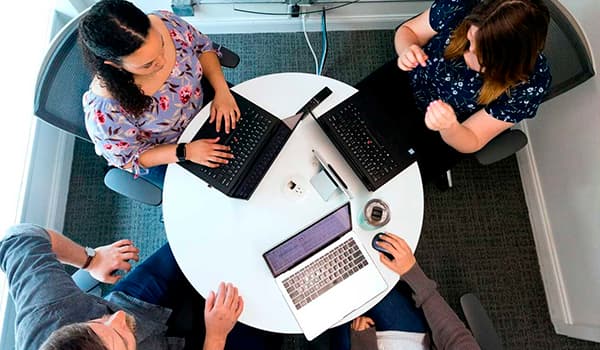 People sitting at a table with laptops in a meeting