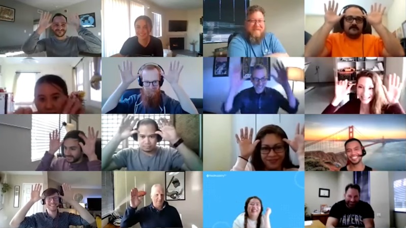 16 people in a video call with their hands raised to their faces